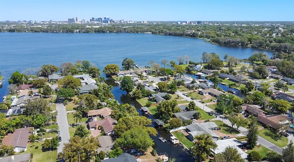 A single-story house with a brick chimney sits on a grassy lawn beside a canal — 2601 WINDWARD COURT, ORLANDO, FL