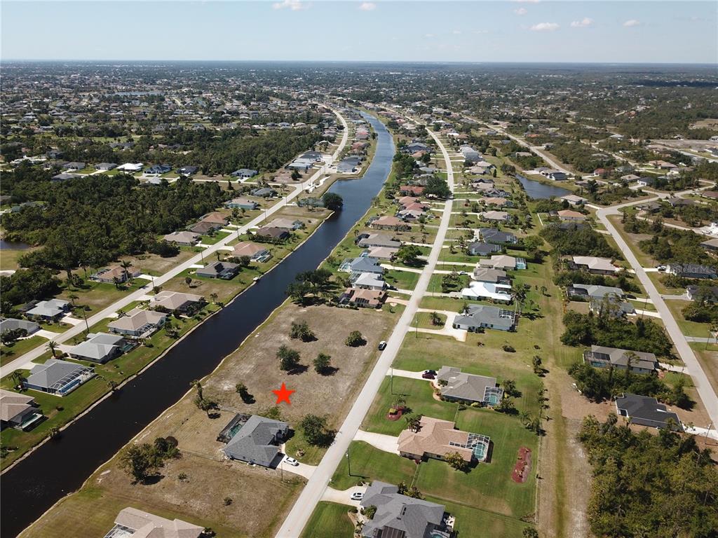 An aerial view shows a vacant residential lot marked with a red star beside a canal — 828 BOUNDARY BOULEVARD, ROTONDA WEST, FL