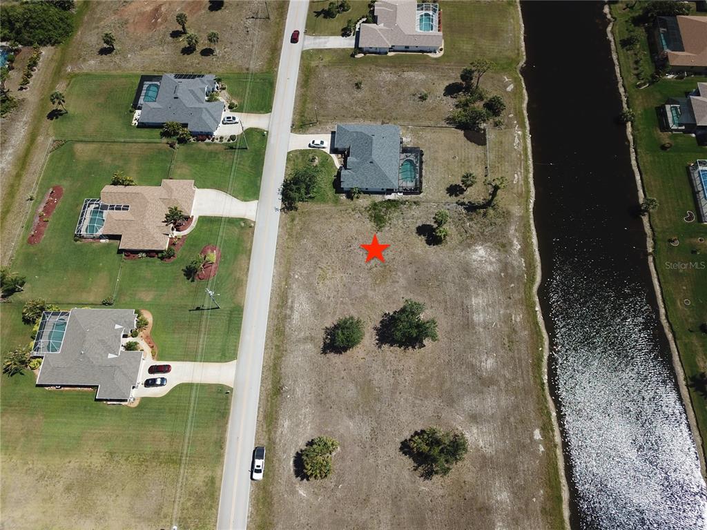 An aerial view shows a vacant residential lot marked with a red star beside a canal — 828 BOUNDARY BOULEVARD, ROTONDA WEST, FL