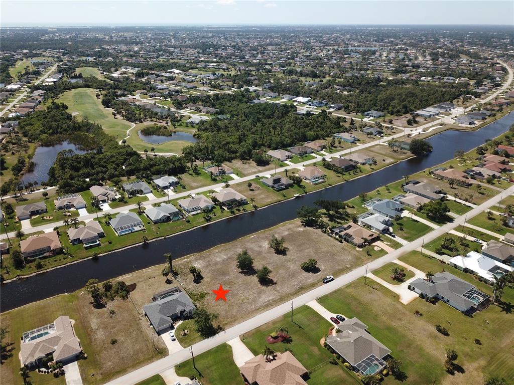 An aerial view shows a vacant residential lot marked with a red star beside a canal — 828 BOUNDARY BOULEVARD, ROTONDA WEST, FL