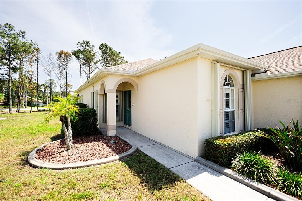 A single-story house with a beige stucco exterior, a tan shingled roof, and a garage — 2542 SANDY HILL COURT, HOLIDAY, FL