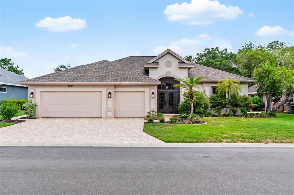 A single-story house with a beige stucco exterior, a three-car garage, and a paved driveway — 6263 AVENTURA DRIVE, SARASOTA, FL