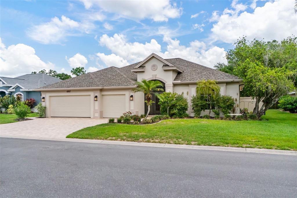 A single-story house with a beige stucco exterior, a three-car garage, and a landscaped yard — 6263 AVENTURA DRIVE, SARASOTA, FL
