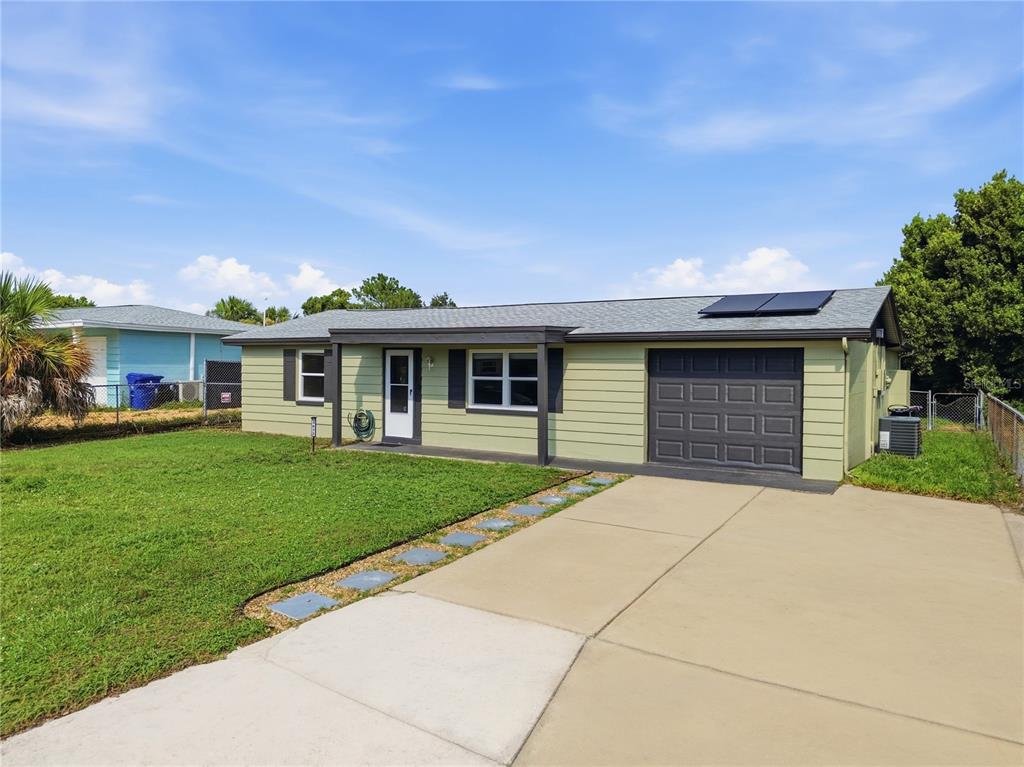 A single-story light green house with a dark garage door and a concrete driveway — 3622 WINDER DRIVE, HOLIDAY, FL