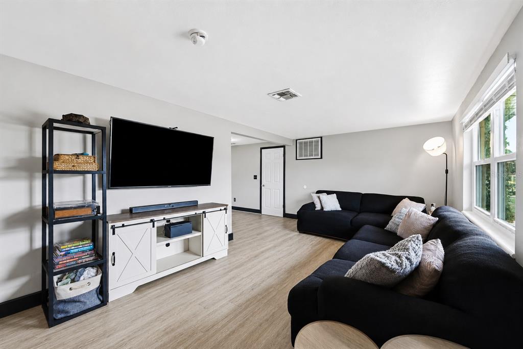 A living room features a black sectional sofa, a wall-mounted television, and a white media console — 3622 WINDER DRIVE, HOLIDAY, FL