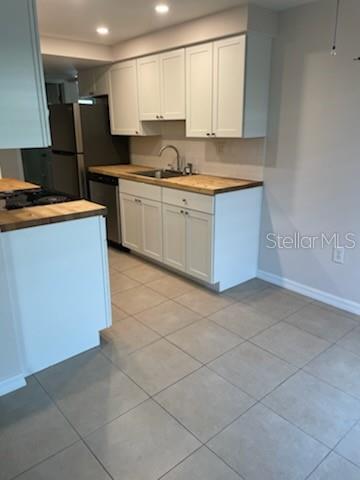 A kitchen features white cabinets, butcher block countertops, and light-colored tile flooring — 208 MAGNOLIA AVENUE UNIT B, ANNA MARIA, FL