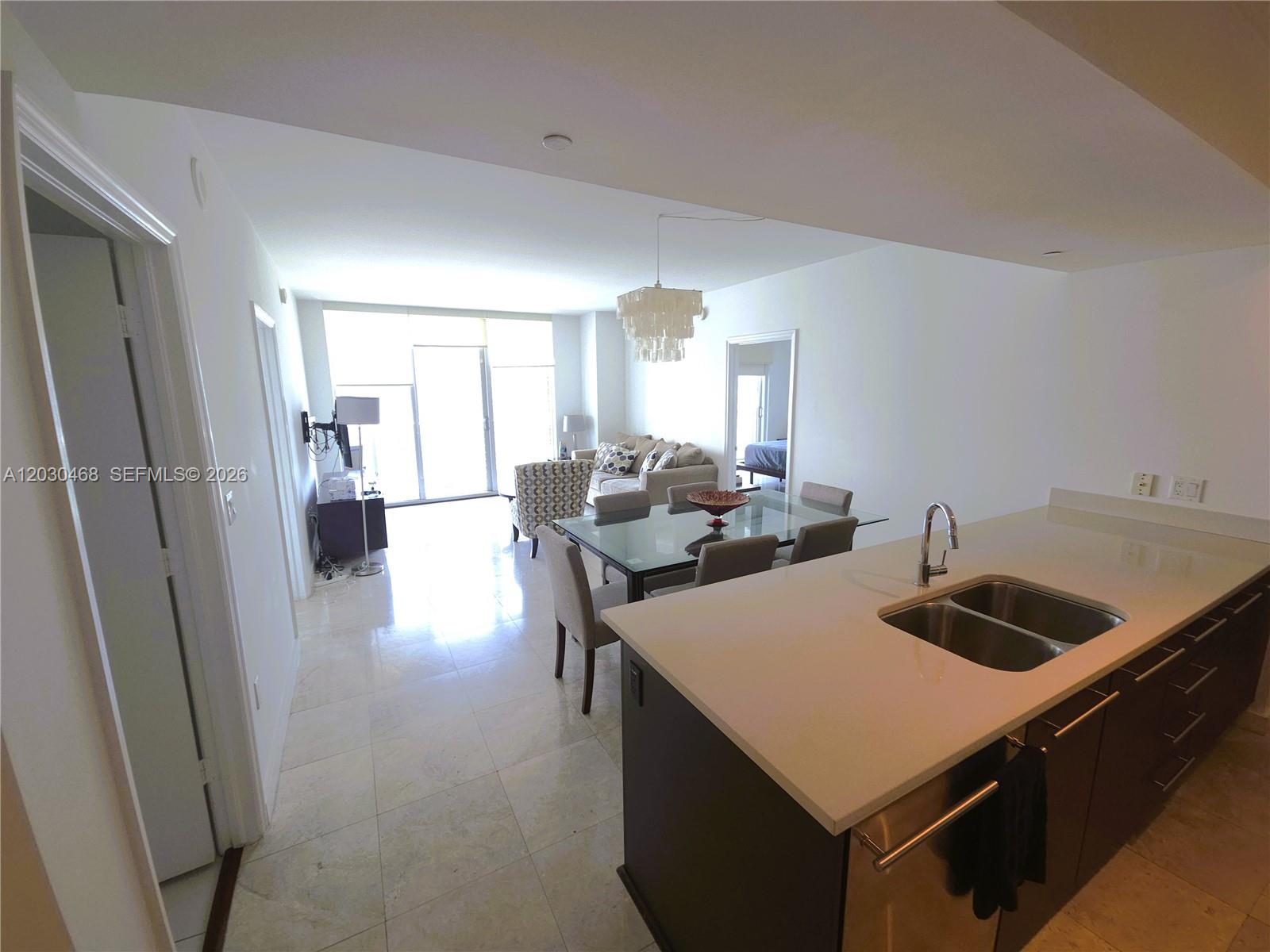 A modern kitchen with a quartz island overlooks an open-concept dining and living area — 500 Brickell Ave # 3105, Miami FL 33131, MIAMI, FL