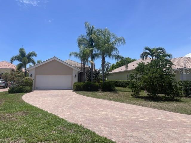 A single-story house with a paved driveway and palm trees under a clear blue sky — 11818 FIORE LANE, SARASOTA, FL