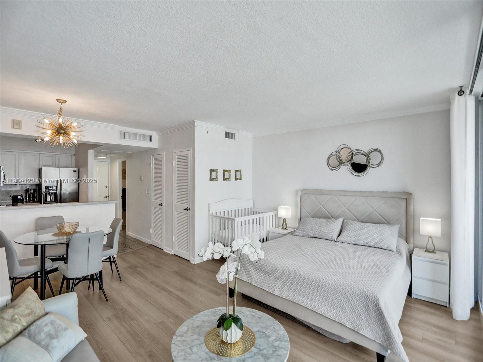 A studio apartment features a bed, a crib, a dining area, and light wood flooring — 2501 S Ocean Dr # 505, Hollywood FL 33019, HOLLYWOOD, FL