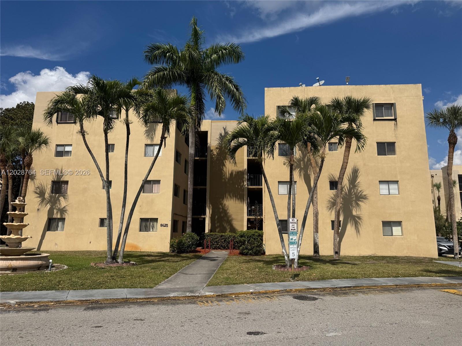 A multi-story tan apartment building features palm trees and a fountain in the front yard — 8625 NW 8th St # 402, Miami FL 33126, MIAMI, FL