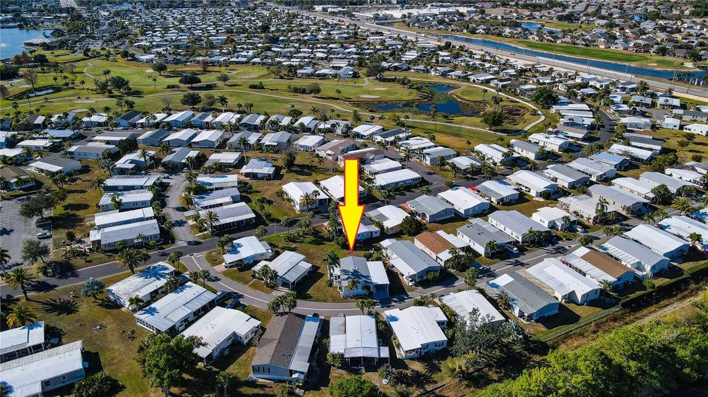 An aerial view shows a single-story house marked by a yellow arrow in a neighborhood — 2100 KINGS HIGHWAY UNIT 401, PORT CHARLOTTE, FL