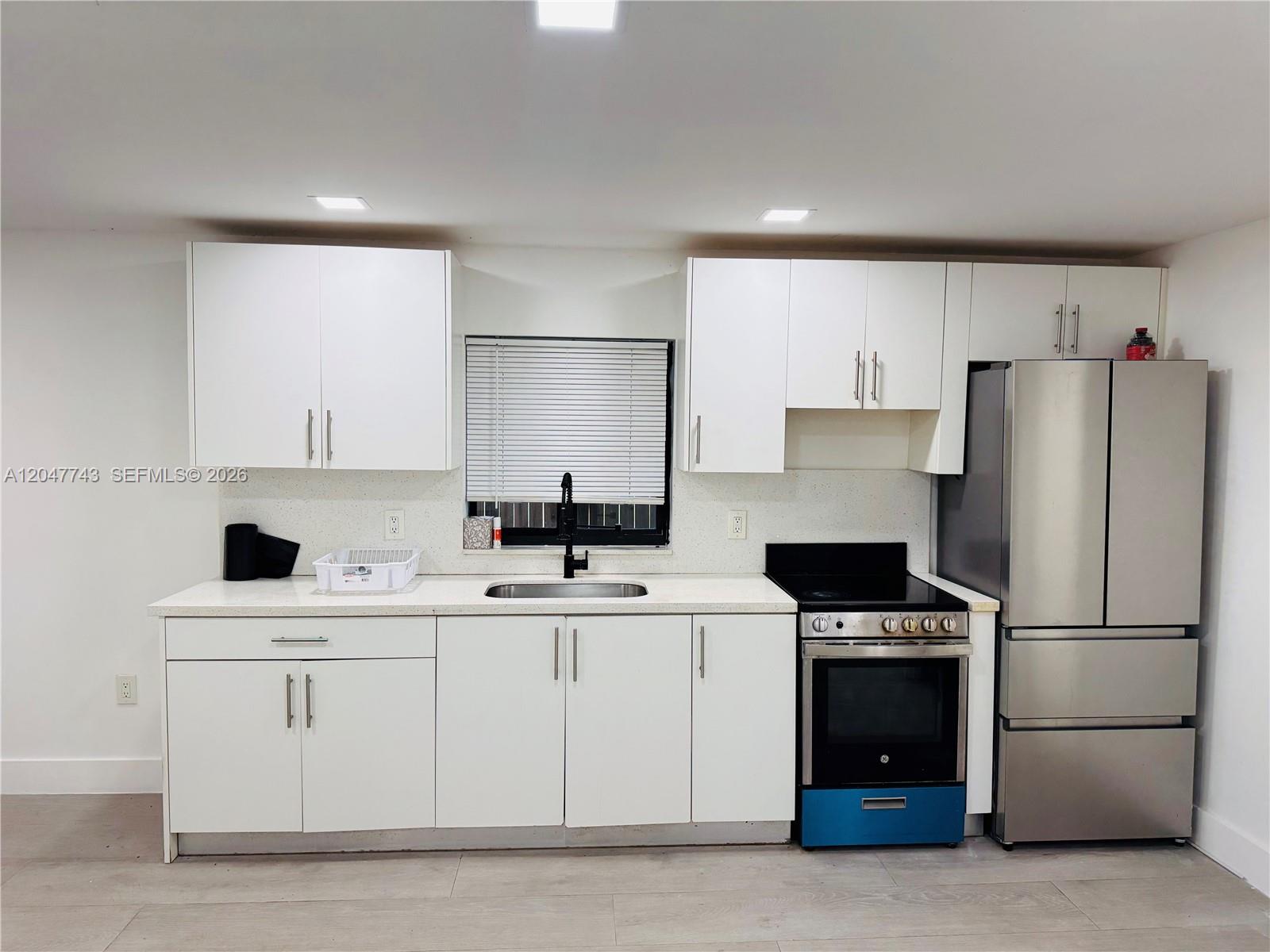 A kitchen features white cabinets, stainless steel appliances, a sink, and light-colored countertops — 520 NW 45th St # 2, Miami FL 33127, MIAMI, FL