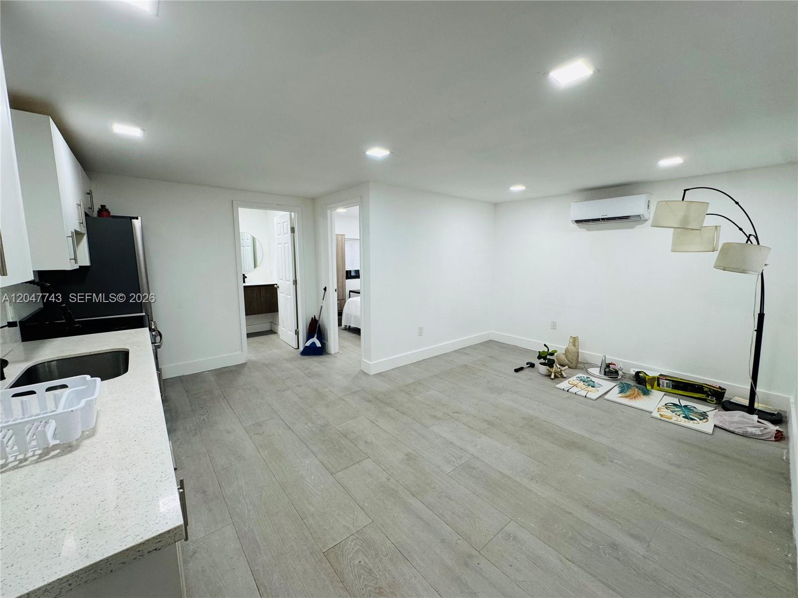 A kitchen area with white cabinets and light wood-look flooring opens into a living space — 520 NW 45th St # 2, Miami FL 33127, MIAMI, FL