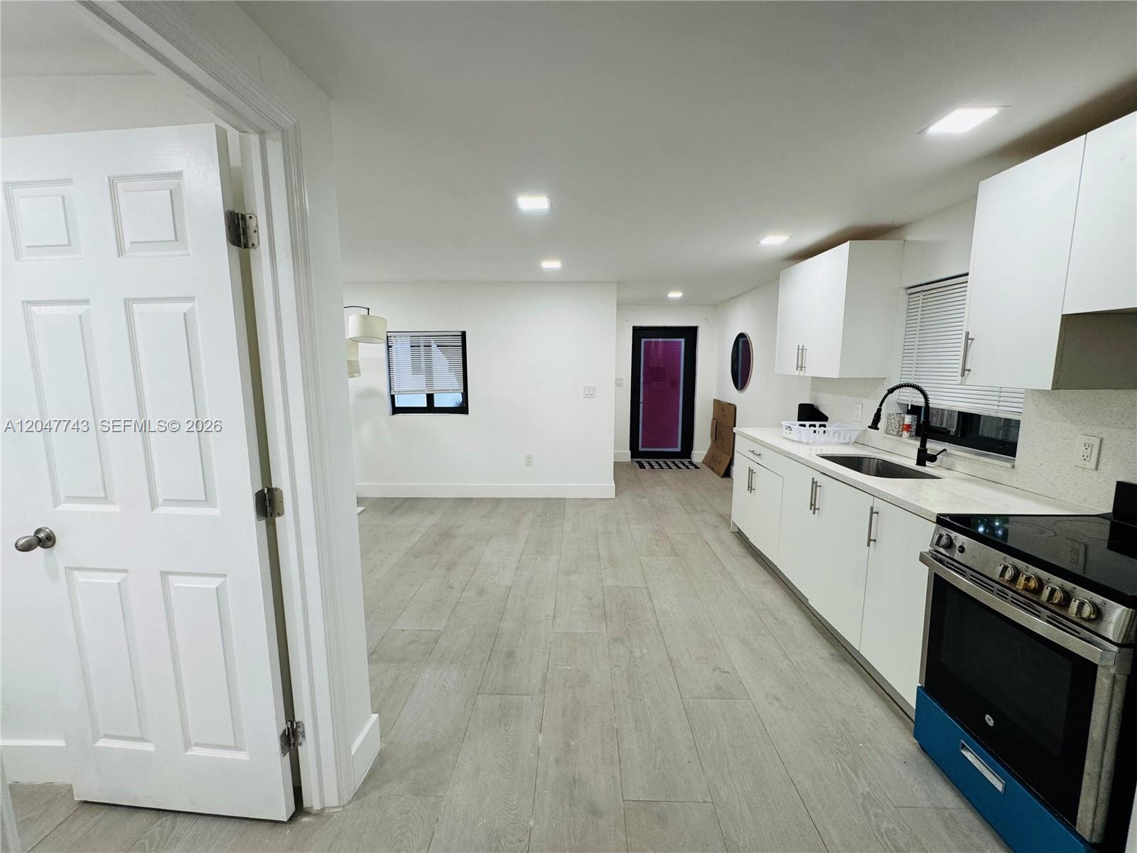A kitchen with white cabinets and stainless steel appliances opens into a living area — 520 NW 45th St # 2, Miami FL 33127, MIAMI, FL