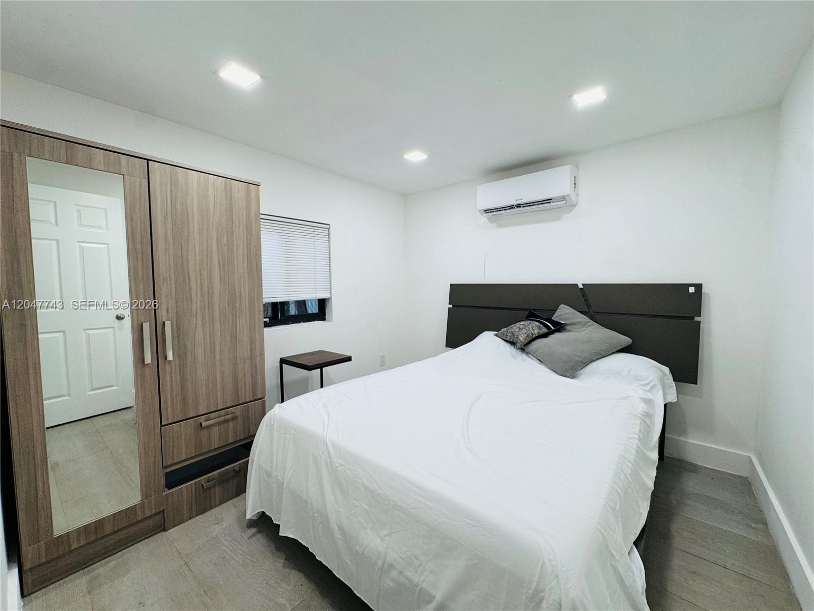 A bedroom features a wooden wardrobe with a mirror, a bed, and a wall-mounted air conditioner — 520 NW 45th St # 2, Miami FL 33127, MIAMI, FL