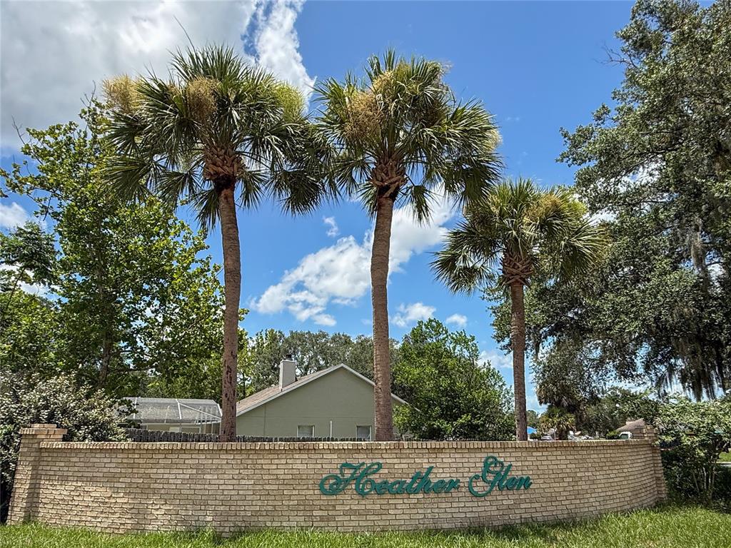 A brick wall with the sign Heather Glen stands before three palm trees and houses — 1367 HENSLEY DRIVE, DELAND, FL
