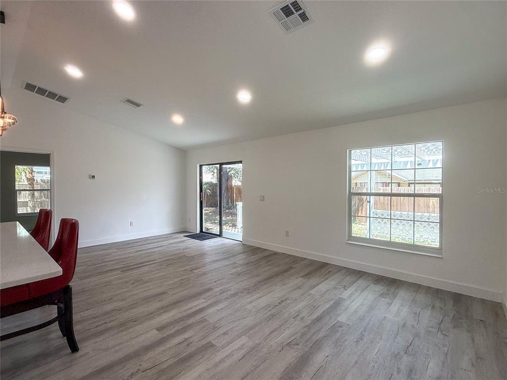An open-concept living area features light wood-look flooring, recessed lighting, and a sliding glass door — 1367 HENSLEY DRIVE, DELAND, FL
