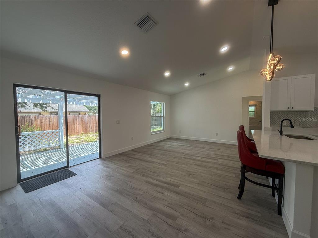An open-concept living area features light wood-look flooring, recessed lighting, and a sliding glass door — 1367 HENSLEY DRIVE, DELAND, FL