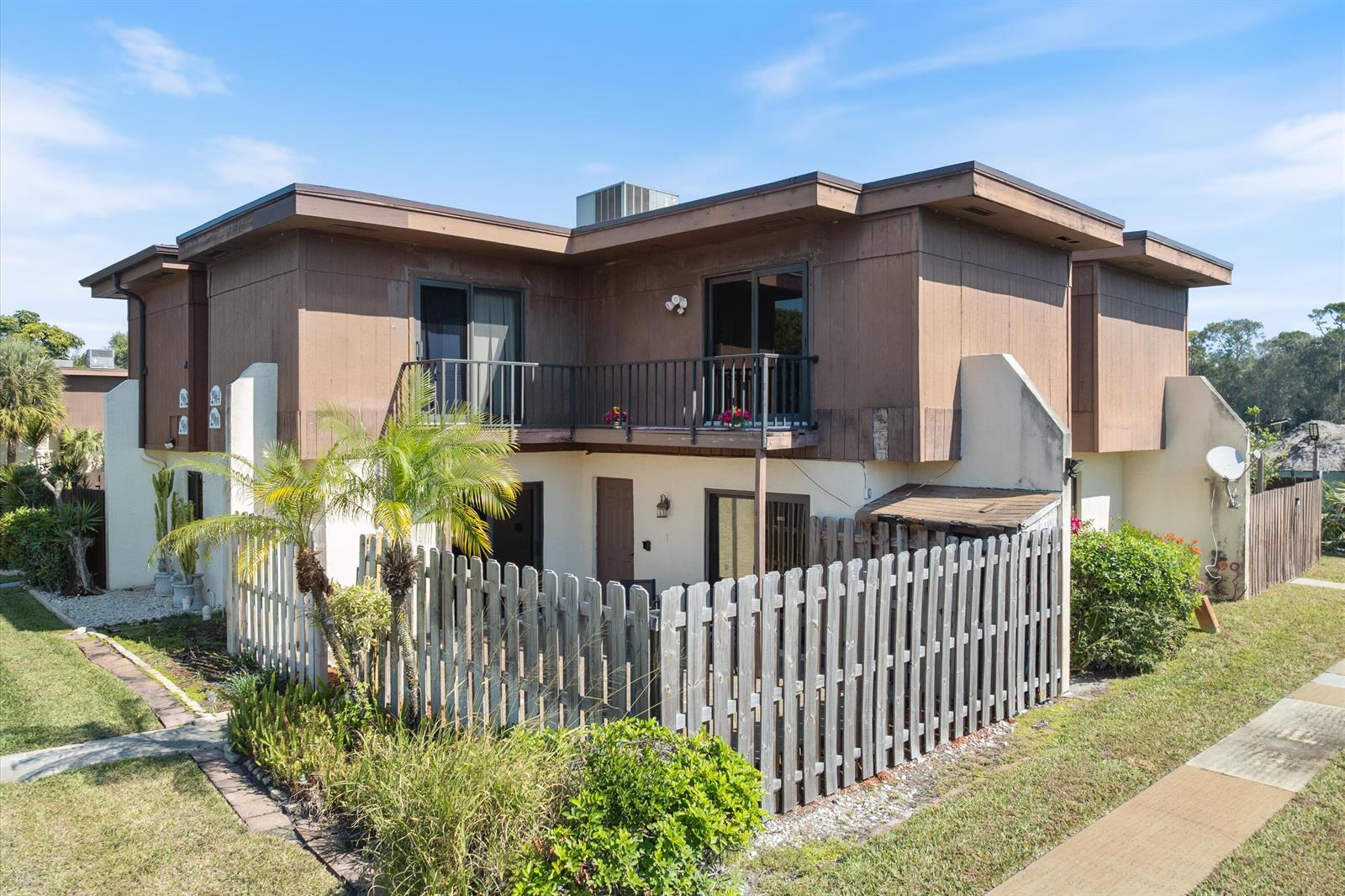 A two-story townhouse with a wooden balcony, fenced patio, and brown exterior siding — 2966 Kirk Road, Lake Worth FL 33461, LAKE WORTH, FL
