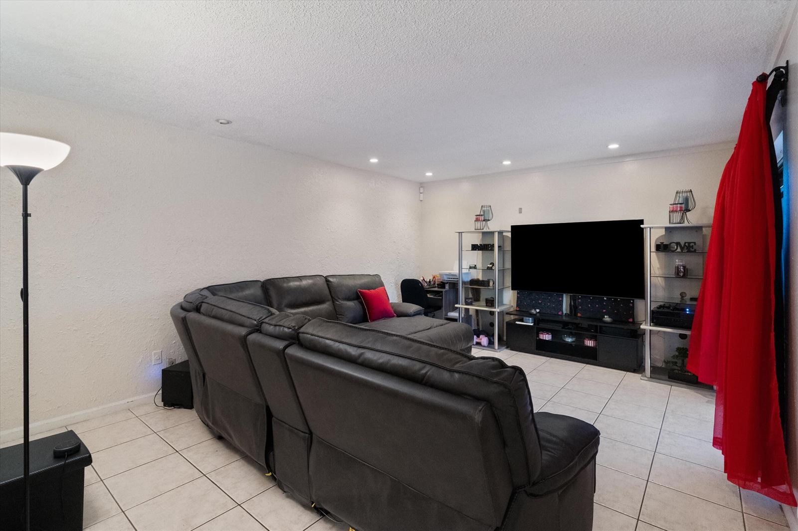 A living room features a large black sectional sofa, a television, and white tiled floors — 2966 Kirk Road, Lake Worth FL 33461, LAKE WORTH, FL