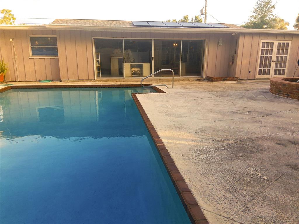 A backyard swimming pool with a concrete patio and a house with sliding glass doors — 3033 DAWSON STREET, SARASOTA, FL