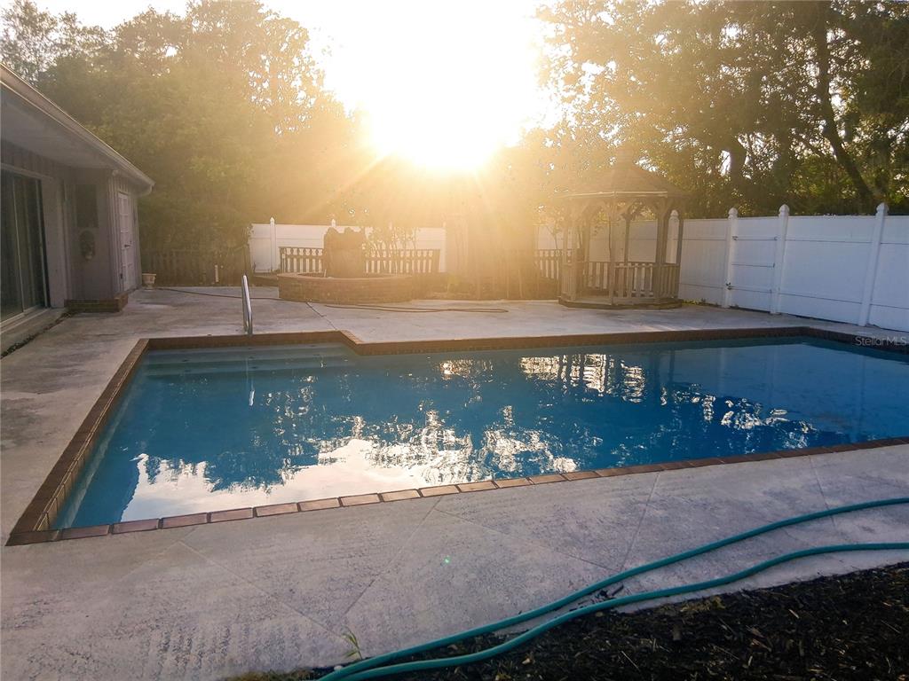 A backyard features a rectangular swimming pool, a gazebo, and a fountain at sunset — 3033 DAWSON STREET, SARASOTA, FL