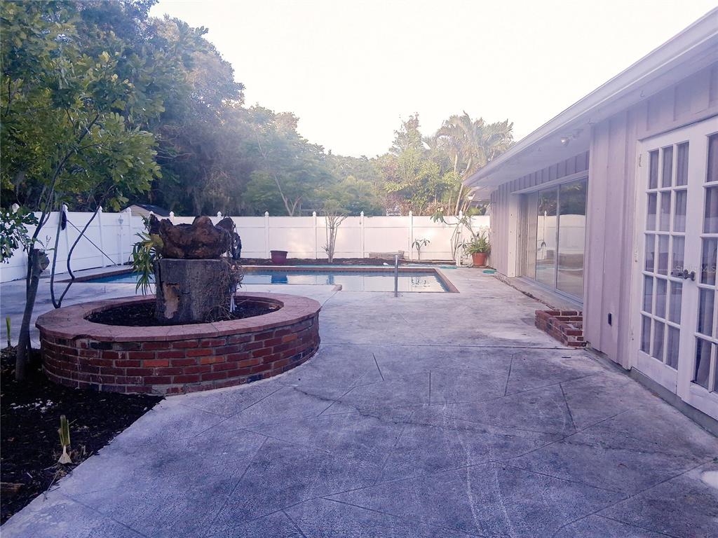 A backyard patio features a brick fountain, a swimming pool, and a white privacy fence — 3033 DAWSON STREET, SARASOTA, FL