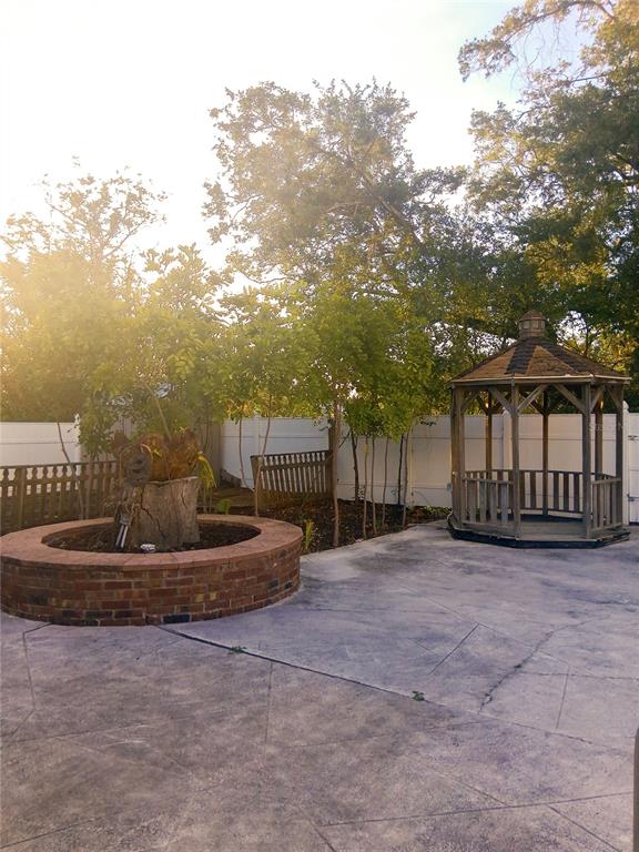 A backyard features a concrete patio, a circular brick planter, and a wooden gazebo — 3033 DAWSON STREET, SARASOTA, FL