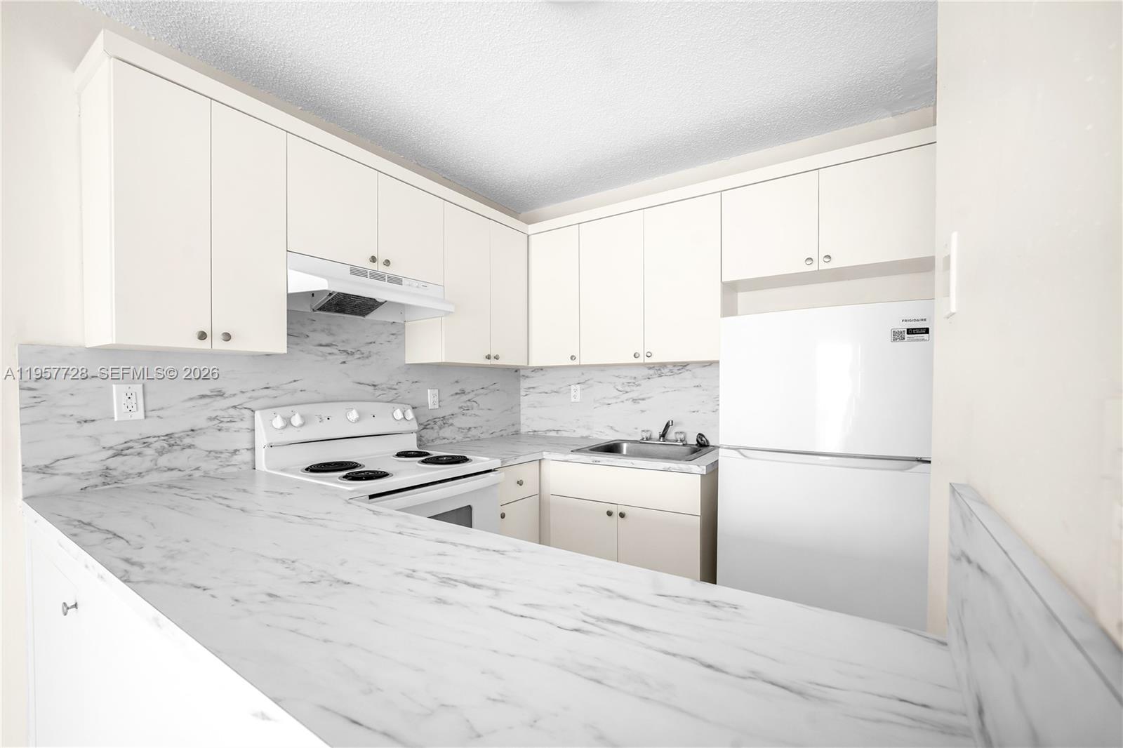A kitchen features white cabinets, marble-patterned countertops, and white appliances — 7805 SW 152nd Ave # 0, Miami FL 33193, MIAMI, FL