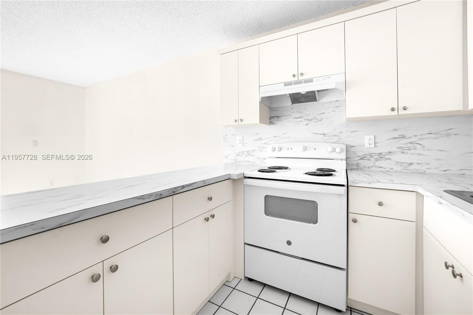 A kitchen features white cabinets, a white stove, and marble-patterned countertops and backsplash — 7805 SW 152nd Ave # 0, Miami FL 33193, MIAMI, FL