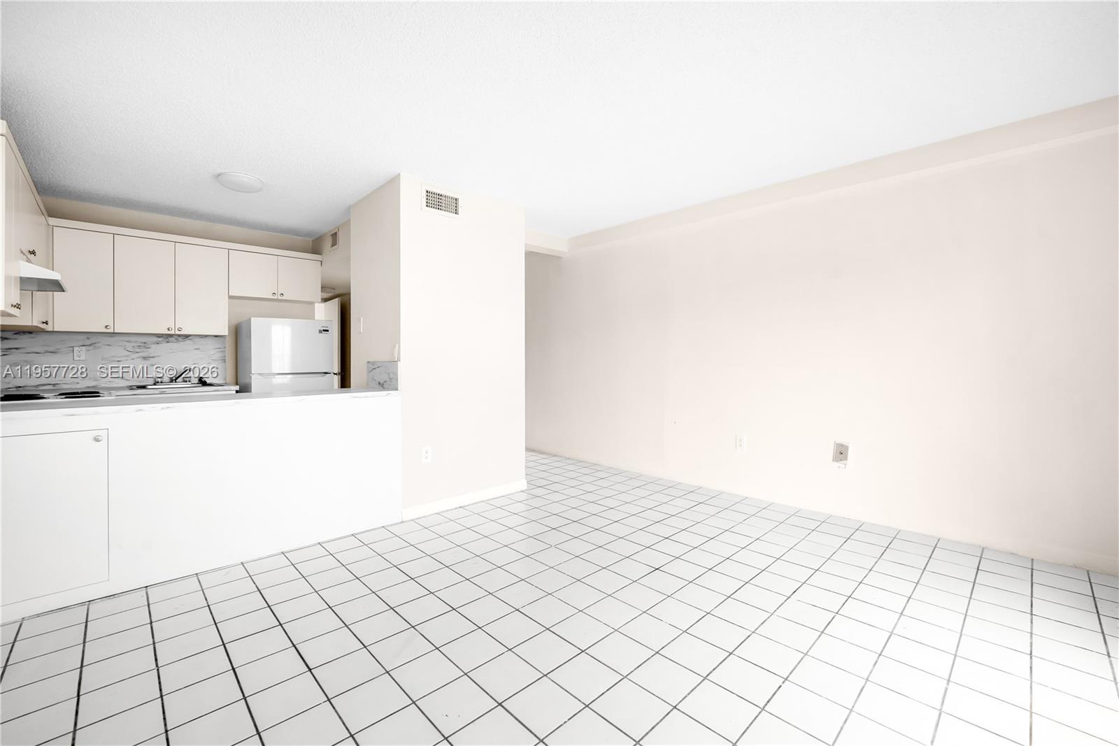 A kitchen with white cabinets and tiled floors opens to an adjacent dining area — 7805 SW 152nd Ave # 0, Miami FL 33193, MIAMI, FL