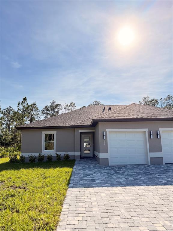 A single-story house with a gray stucco exterior, a paved driveway, and a two-car garage — 11 SEWARD TRAIL E UNIT A, PALM COAST, FL