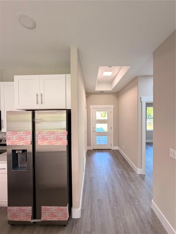 A stainless steel refrigerator stands next to a hallway leading to a front door — 11 SEWARD TRAIL E UNIT A, PALM COAST, FL