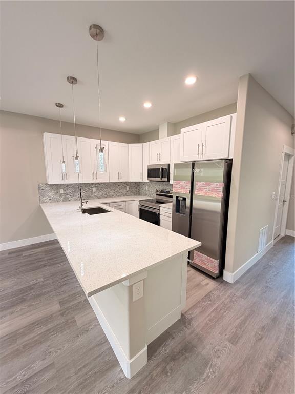 A modern kitchen features white cabinets, a quartz island, stainless steel appliances, and wood flooring — 11 SEWARD TRAIL E UNIT A, PALM COAST, FL