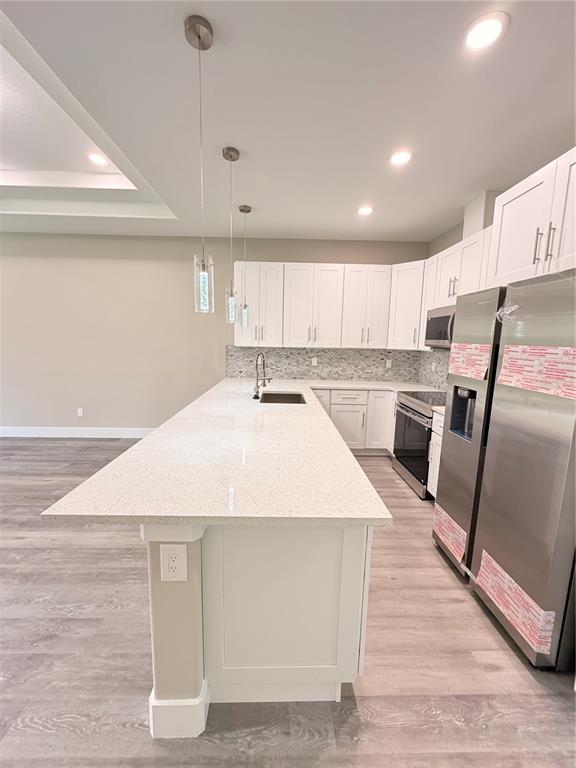 A modern kitchen features white cabinets, a large quartz island, and stainless steel appliances — 11 SEWARD TRAIL E UNIT A, PALM COAST, FL