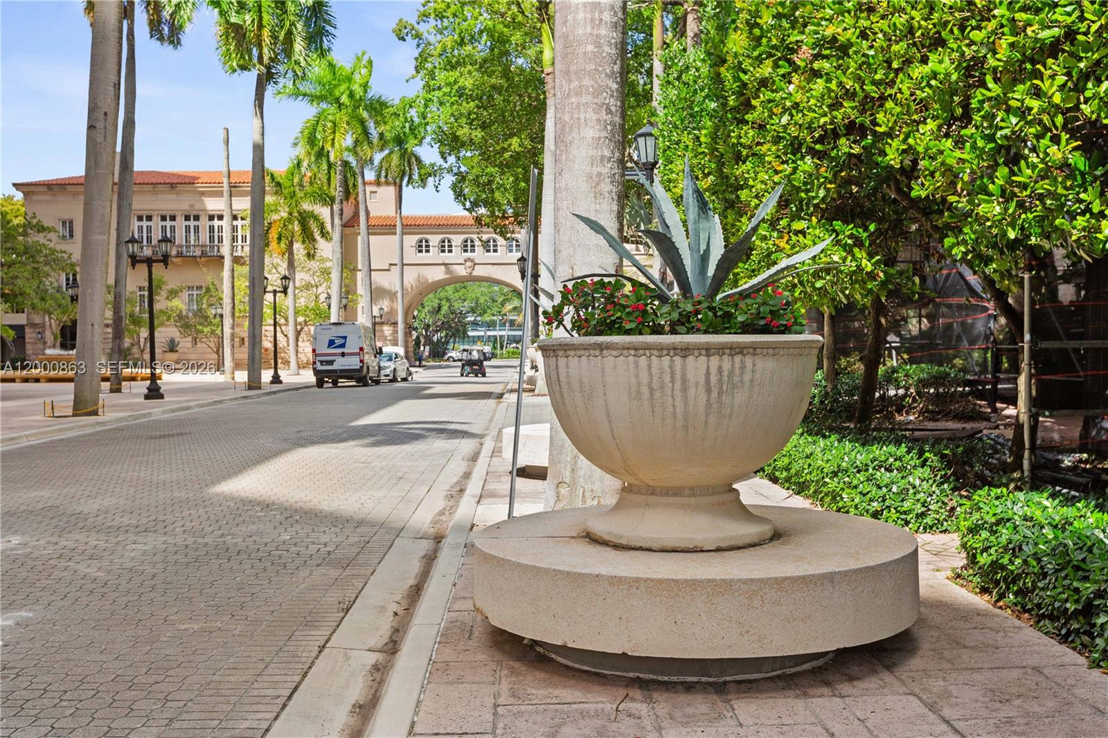 A stone planter with agave sits on a sidewalk near a street with palm trees — 888 S Douglas Rd, Coral Gables FL 33134, CORAL GABLES, FL