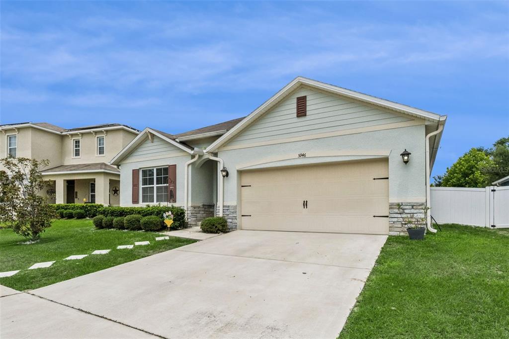 A single-story house with a light-colored stucco facade, stone accents, and a two-car garage — 5946 CHURCHILL SQ WAY, GROVELAND, FL