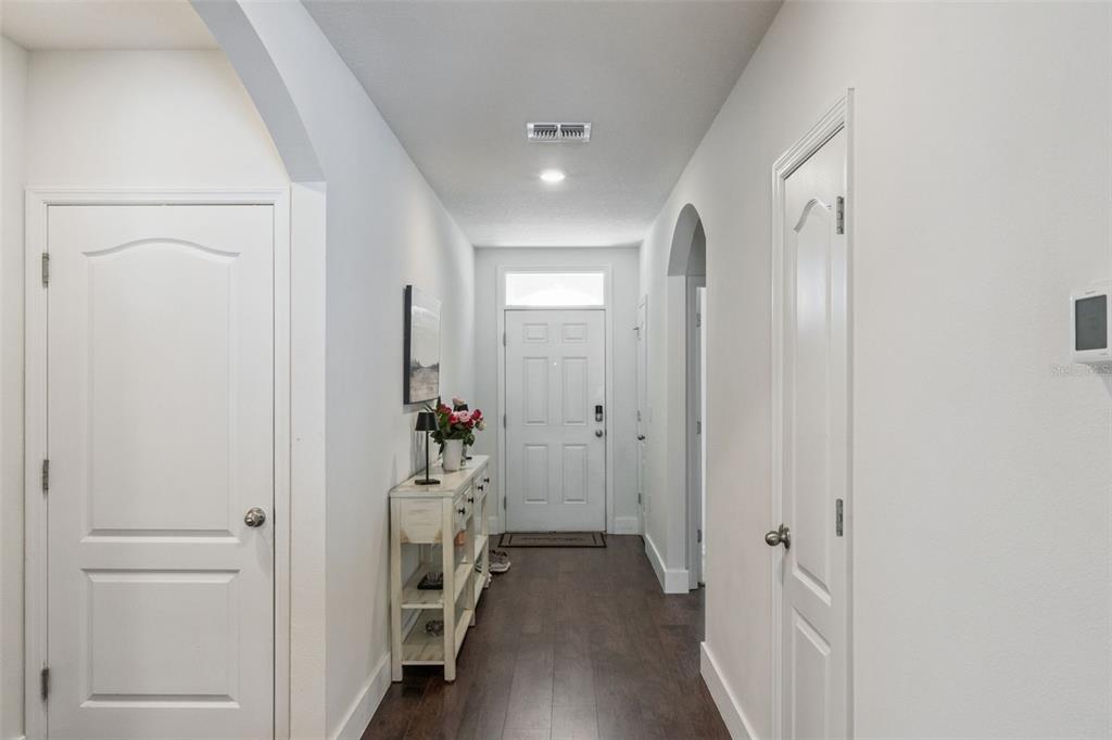 A bright entryway features white walls, dark wood flooring, and a white front door — 5946 CHURCHILL SQ WAY, GROVELAND, FL