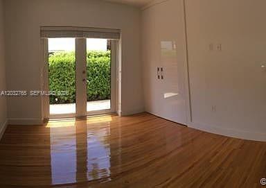 A room with hardwood floors, white walls, and glass French doors leading to a hedge — 3 Farrey Ln # 3, Miami Beach FL 33139, MIAMI BEACH, FL