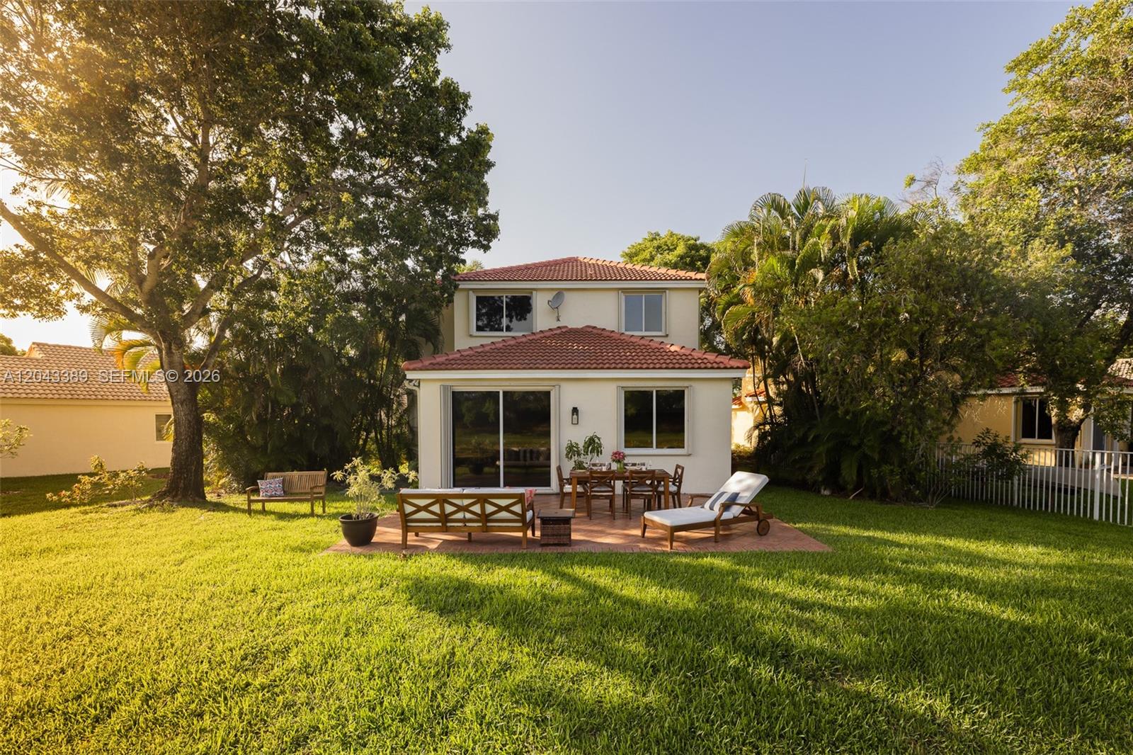 The exterior view shows a two-story house with a patio, outdoor furniture, and a lawn — 4275 Ironwood Ct, Weston FL 33331, WESTON, FL