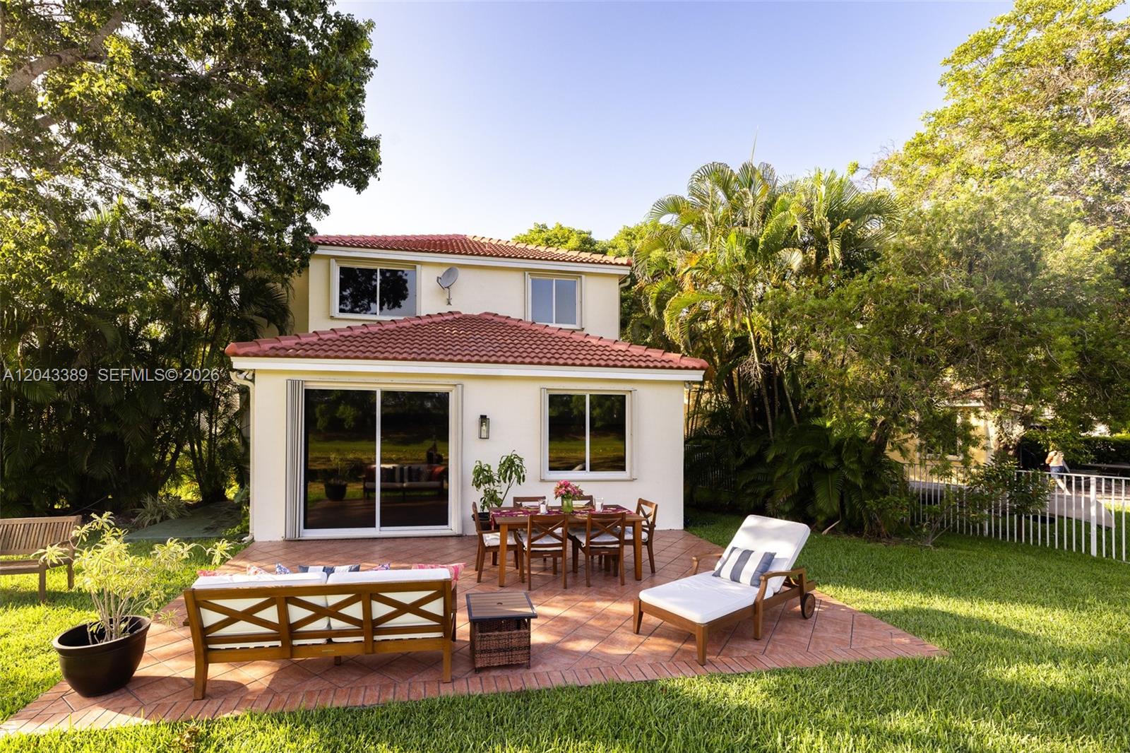 A two-story house features a tiled patio with outdoor furniture and a grassy backyard — 4275 Ironwood Ct, Weston FL 33331, WESTON, FL