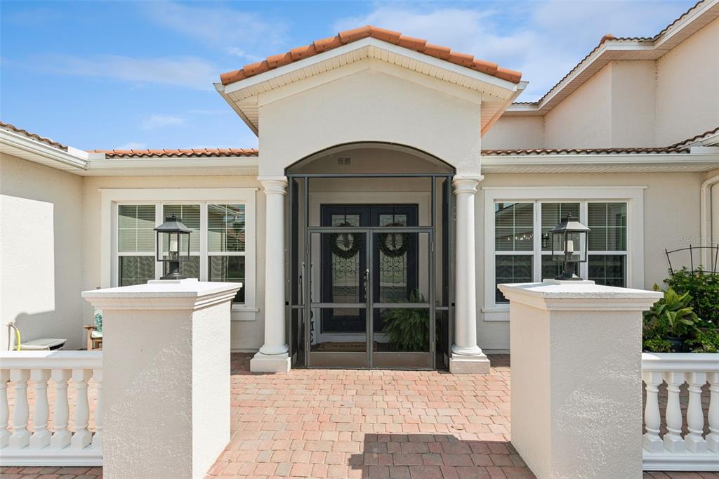 The exterior of a house features a paved walkway leading to a screened-in double front door — 3713 DOCKSIDE DR, KISSIMMEE, FL