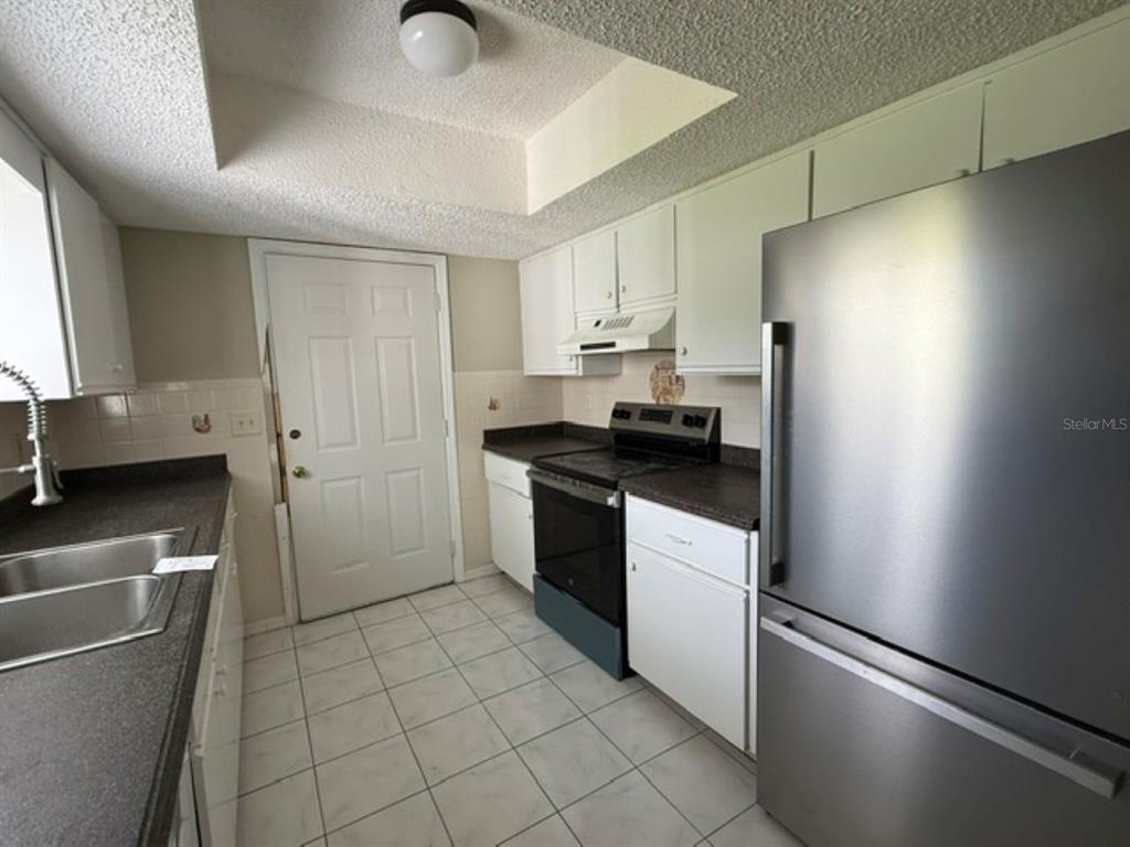 A kitchen with white cabinets, dark countertops, stainless steel appliances, and white tile flooring — 10235 SE 178TH PLACE, SUMMERFIELD, FL