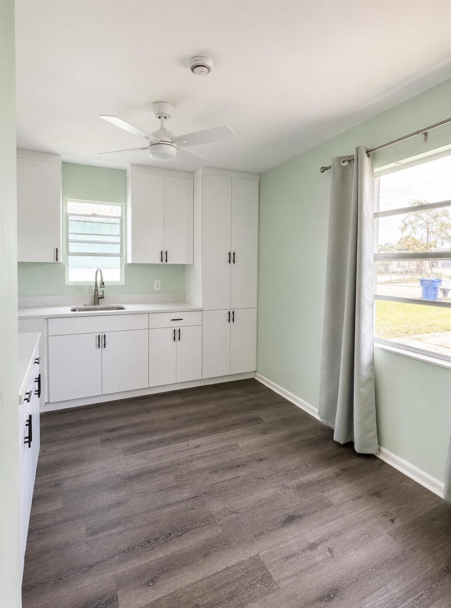 A kitchen with white cabinets, a sink, light green walls, and dark wood-look flooring — 1328 W 6th Street, Riviera Beach FL 33404, RIVIERA BEACH, FL