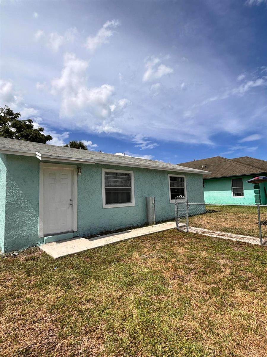 A light blue, single-story house exterior with a white door and two windows — 1328 W 6th Street, Riviera Beach FL 33404, RIVIERA BEACH, FL