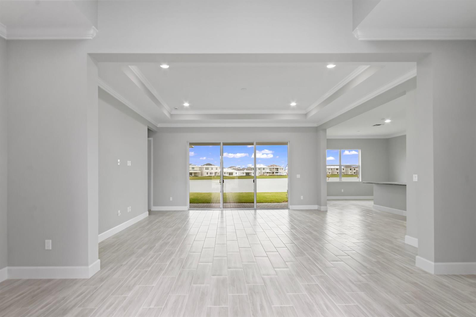 An empty living room features light gray walls, wood-look tile flooring, and sliding glass doors — 5182 Liberty Lane, Westlake FL 33470, WESTLAKE, FL