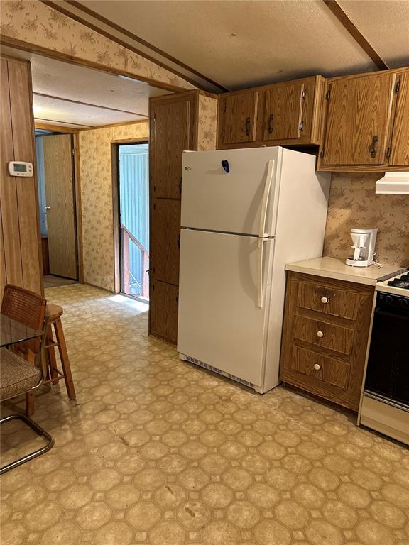 A kitchen features wood-grain cabinets, a white refrigerator, and patterned vinyl flooring — 13059 NE 44TH LANE, SILVER SPRINGS, FL