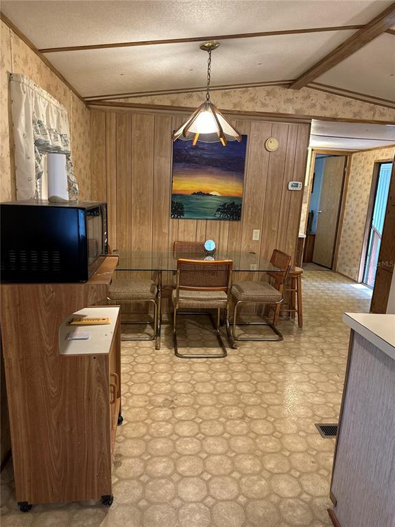 A dining area features wood-paneled walls, a glass-topped table with cane chairs, and vinyl flooring — 13059 NE 44TH LANE, SILVER SPRINGS, FL