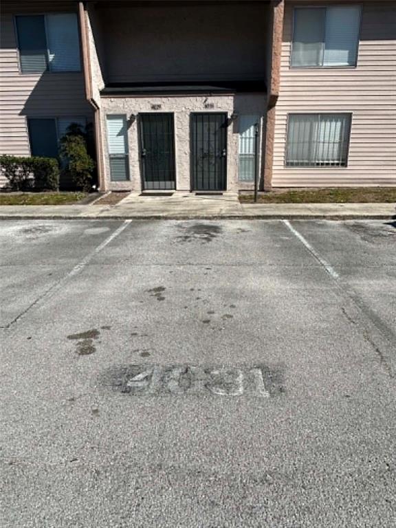 A two-story apartment building exterior features two front doors and a paved parking space — 4031 HENLEY ROAD UNIT 1706, ORLANDO, FL