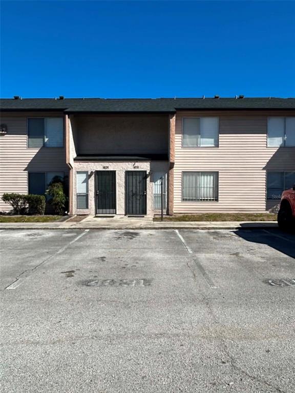 A two-story apartment building with light-colored siding and a paved parking lot in front — 4031 HENLEY ROAD UNIT 1706, ORLANDO, FL